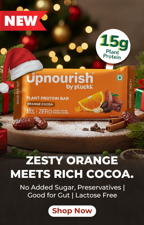 Upnourish plant protein bar with Christmas decorations in the background. A banner representing wintr and christmas vides in the background while text read new zesty orange meets rich cocoa no added sugar no added preservative good for gut lactose free shop now 15g protein Upnourish, plant protein bar, plant protein bar india, orange protein bar, ornage coco plant protein bar, 15 gram, offer 20% off,  coupen code 